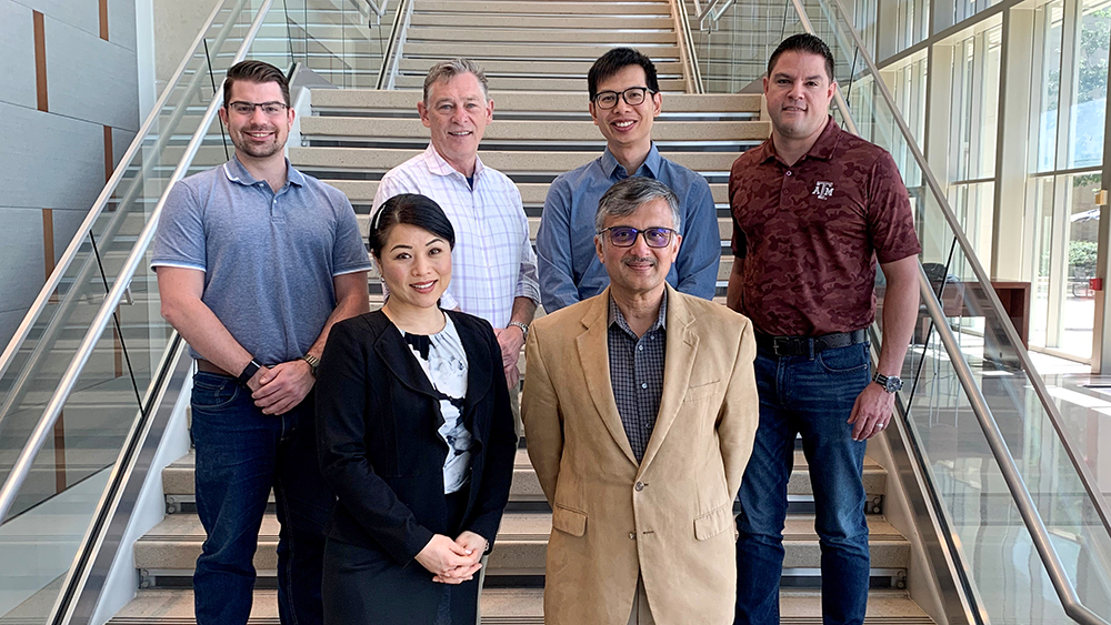 Six nicely-dressed members of the Data Engineering Advisory Council are smiling and standing on a wide staircase.