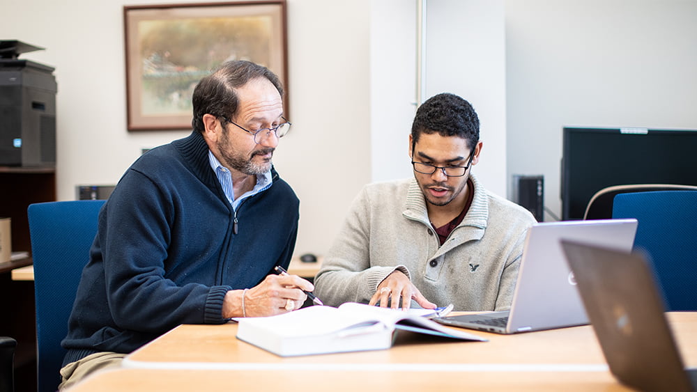 Student working with an advisor at a table. 