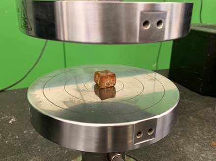 An additive manufactured non-metallic sample sits on a metal plate on lab machinary 