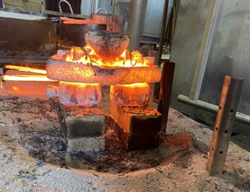 A mold is cast in metal and is engulfed in flames as it sets