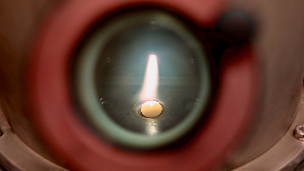 A flame heats up NiTiHf HTSMAs inside a vacuum arc melter during fabrication of the material.