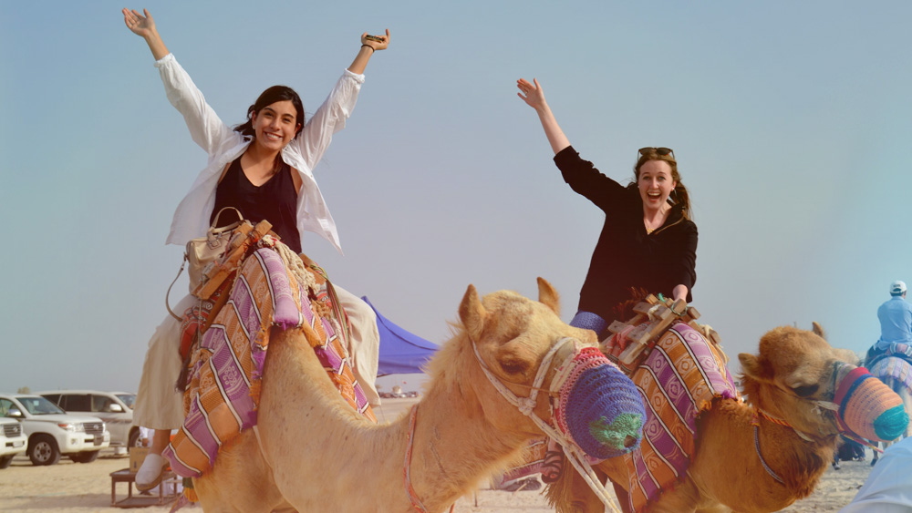 Ashley Taylor and friend on back of camels in Qatar. 