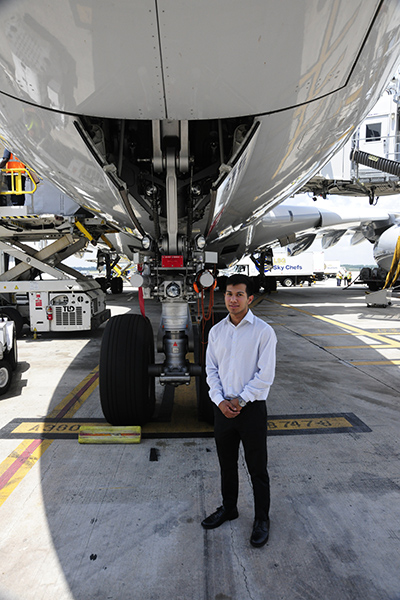 Giovanni Fuentes, an industrial and systems engineering student, stands next to an airplane at his internship.