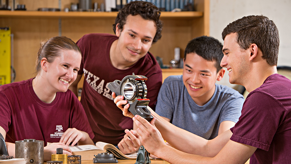 Four smiling students look at engineering project