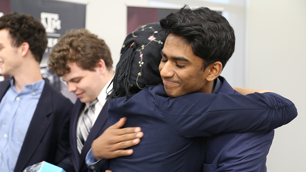 Students hug, one student smiling, during event.