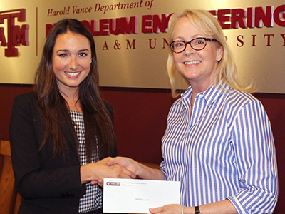 Cathy Sliva handing scholarship notice to smiling petroleum female student