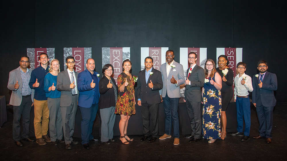 Group photo of fourteen recipients of the 2019 Distinguished Student Award. All are giving a thumbs up hand sign.