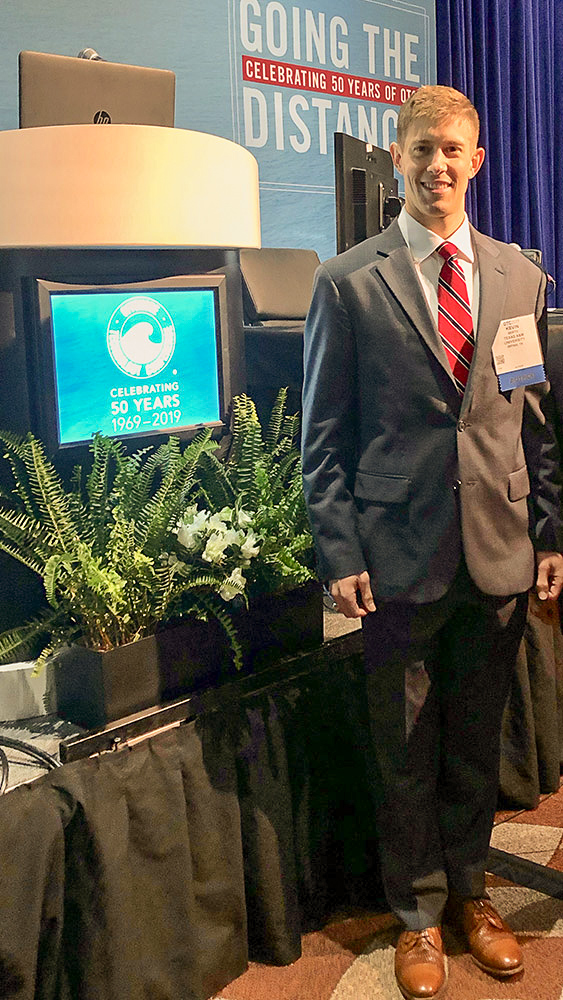 Berto stands in front of the stage at the 2019 SNAME conference.