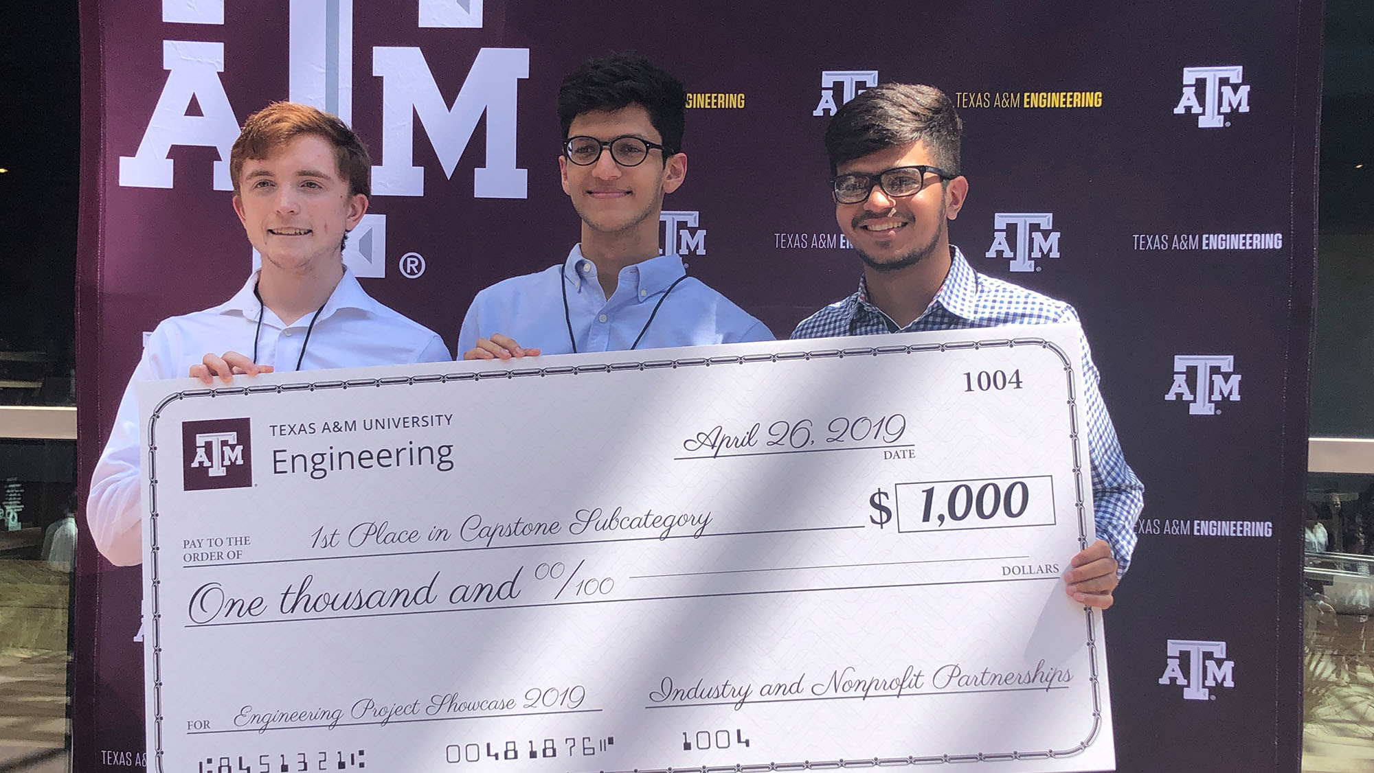 Team members pose in front of a maroon Texas A&M backdrop after being awarded a check for their research project.