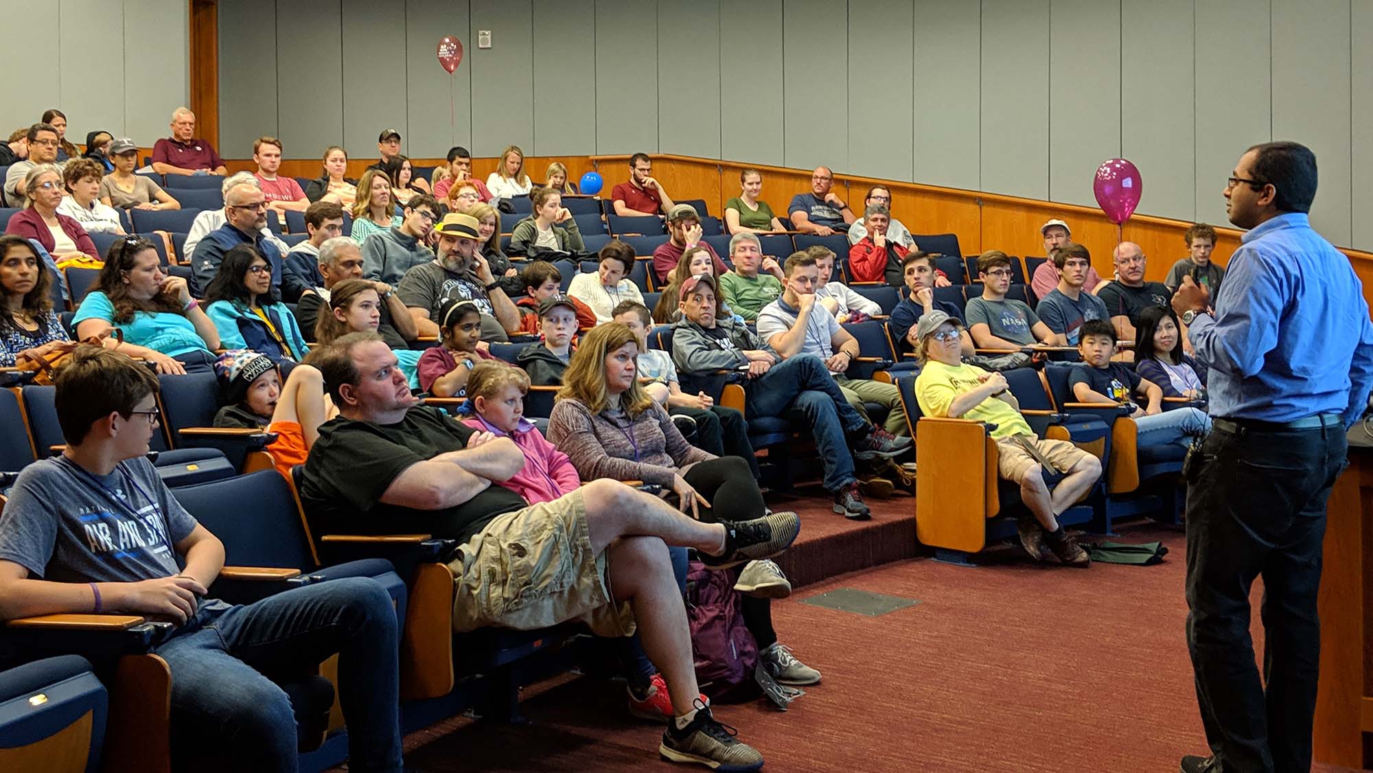 Prospective students and their parents listen to the professor's presentation in a lecture hall on campus.