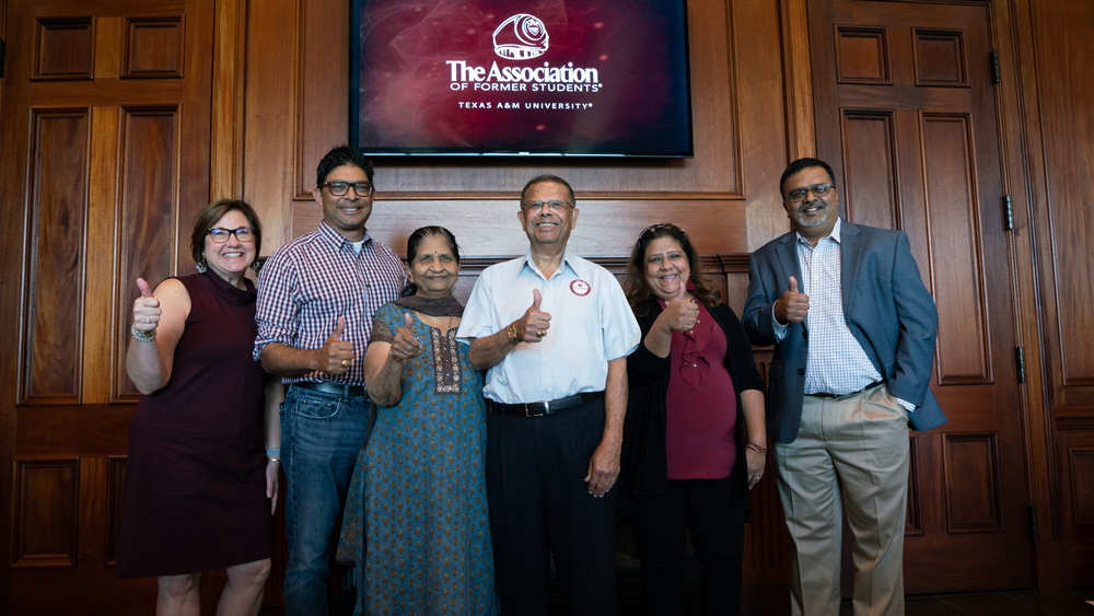 Dilipkumar Patel ’66 surrounded by his wife, daughter, chemical engineering department head and family friends from The Association of Former Students giving a gig 'em hand sign.