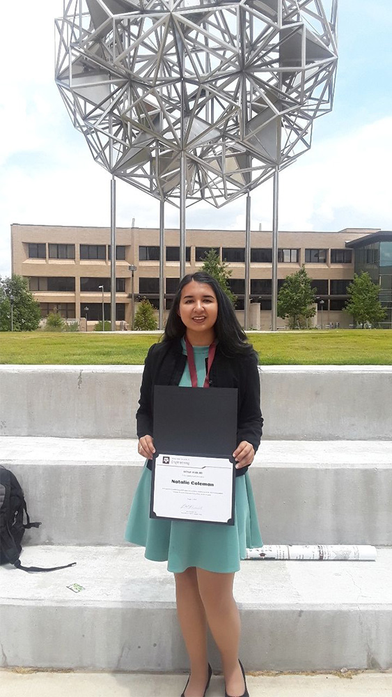Natalie Coleman stands in front of the Engineering Quad with her certificate.