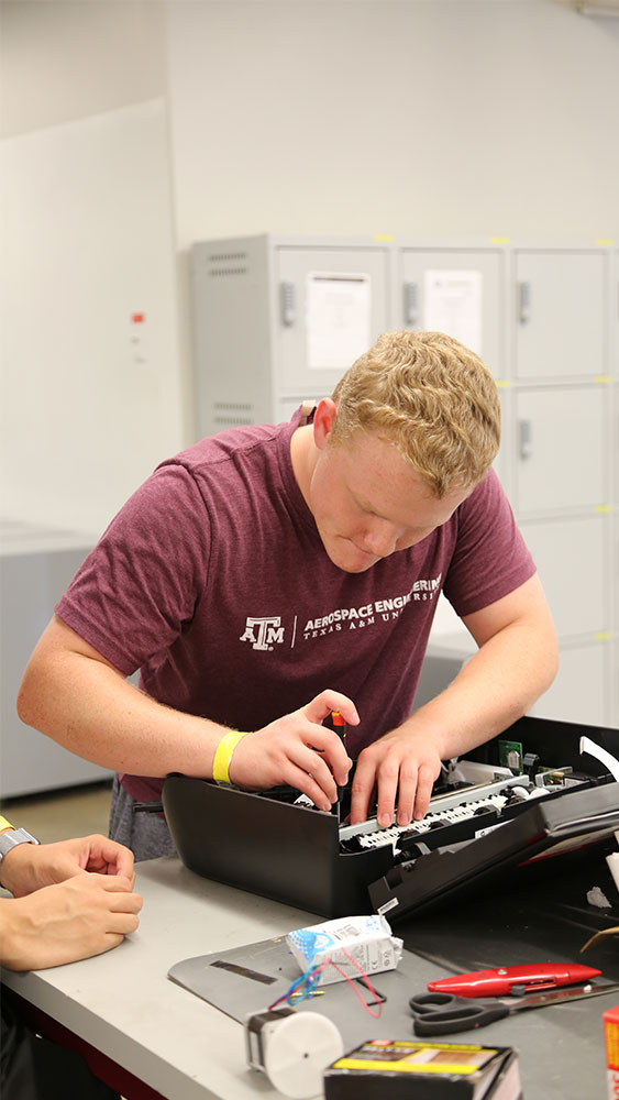 Male student disassembling printer for Aggies Invent - Nuclear Security