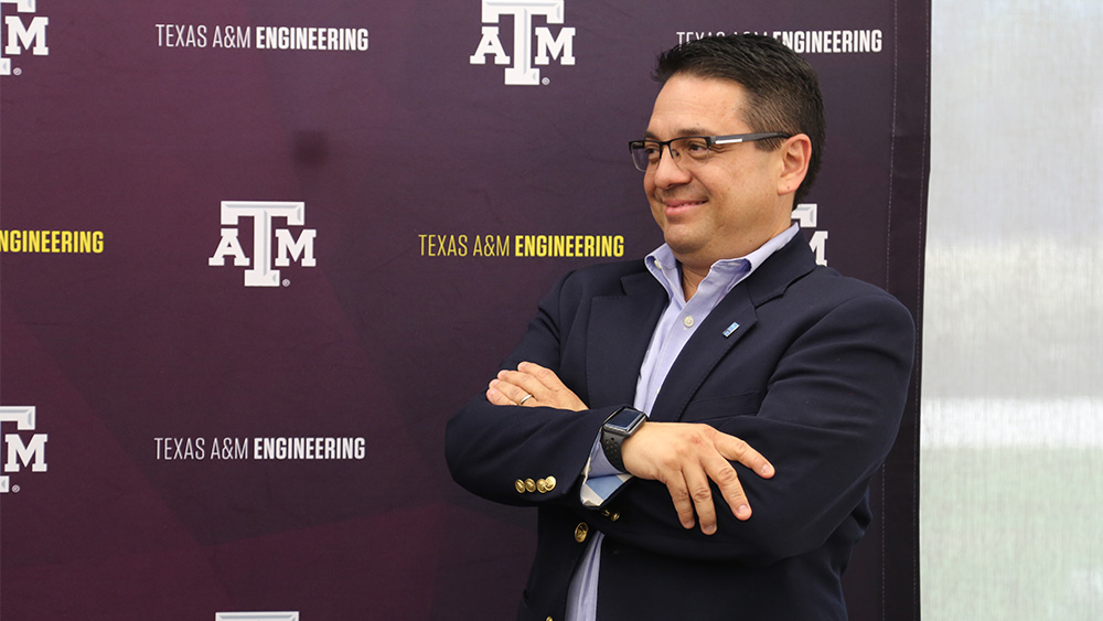 A man wearing glasses smiles in front of a backdrop that says "Texas A&amp;M Engineering"