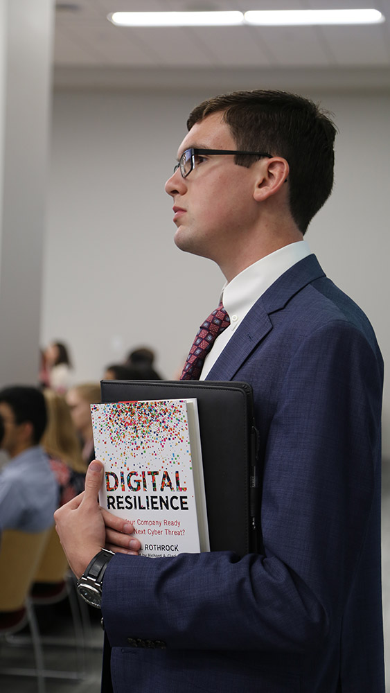 Student holds Ray Rothrock's book, Digital Resilience