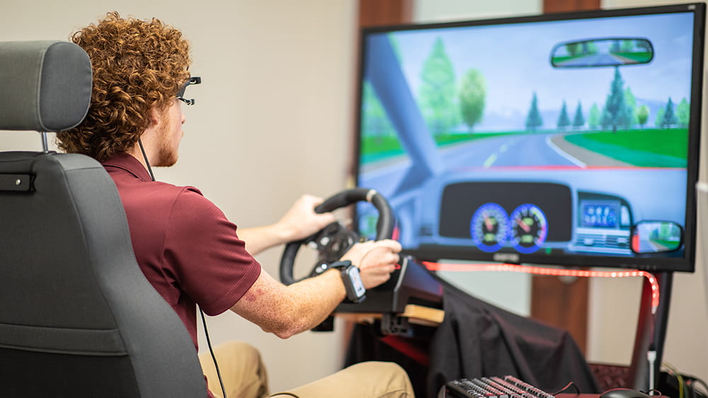 Student using a driving simulator in a lab. 