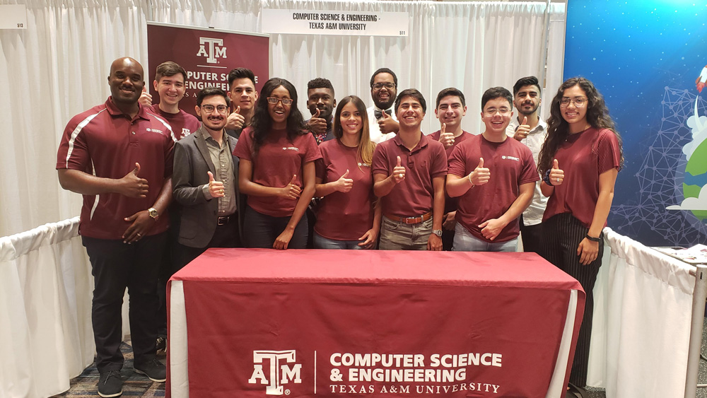 Dr. David Kebo with group of 12 male and female students smiling and giving "gig 'em" hand sign.