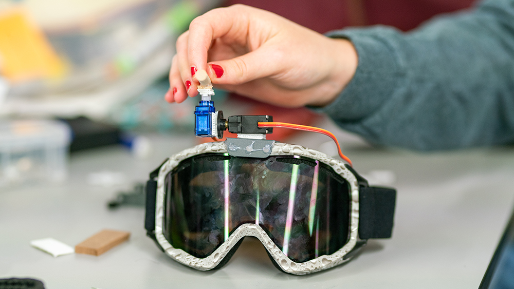 A girl is touching a pair of goggles made at Aggies Invent.
