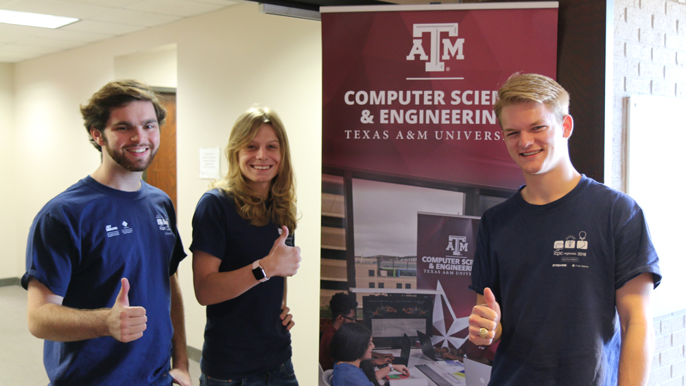 Computer science and engineering students Julia Graham, Tanner Hoke and Nathan Mandell, standing in front of banner with department name on it giving thumbs up hand sign.