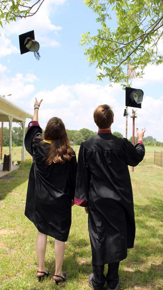 Katie and Steven, former aerospace engineering students, have their backs to the camera and are dressed in their Texas A&amp;M graduation gowns, tossing their caps into the air.