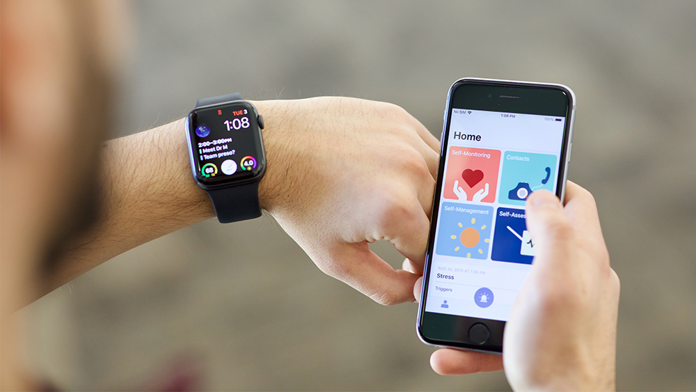 Student holding a smart phone in one hand with a smartwatch on the other wrist while using a new mental health app. 