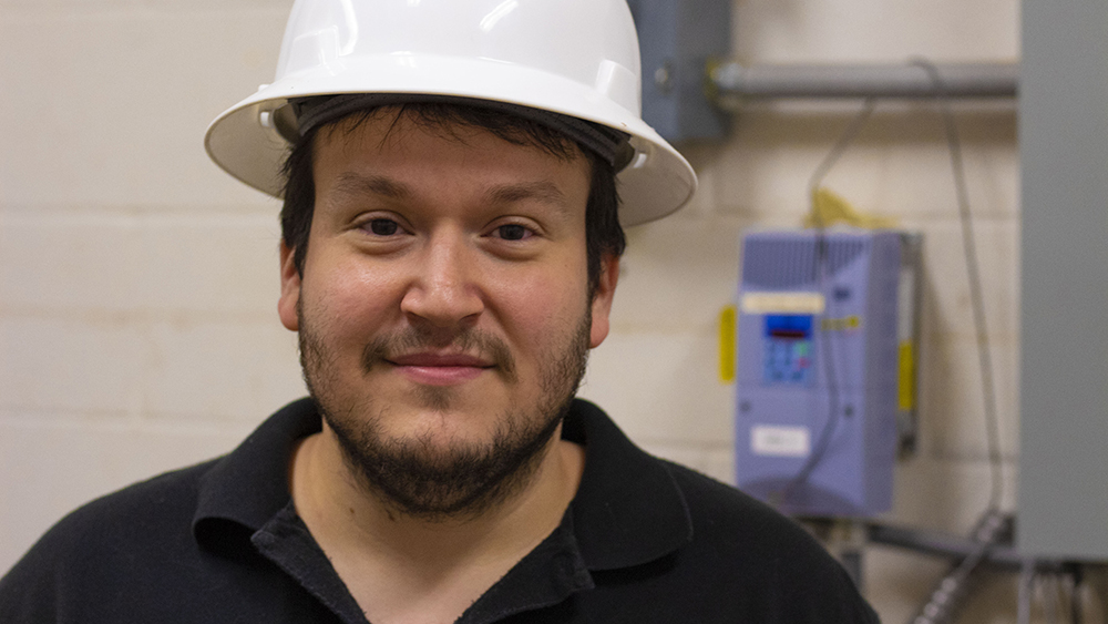 graduate engineering student Omer Kaldirim wears a hard hat while working in the tower lab basement pump room of the Richardson Building