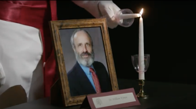 Framed photo of William Hyman next to candle being lit during 2020's Aggie Muster ceremony.