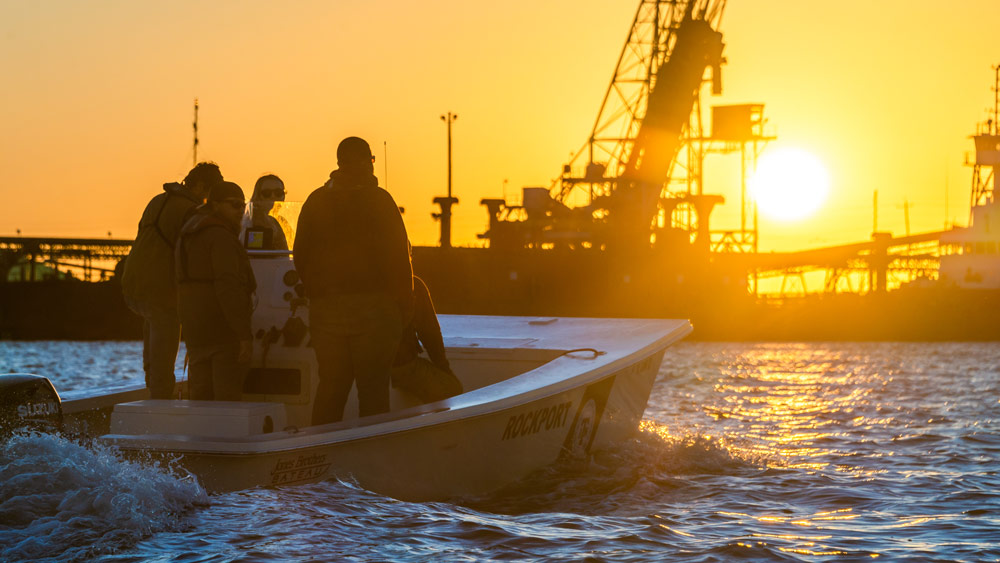 Texas A&amp;M Galveston students standing on a boat at sunset