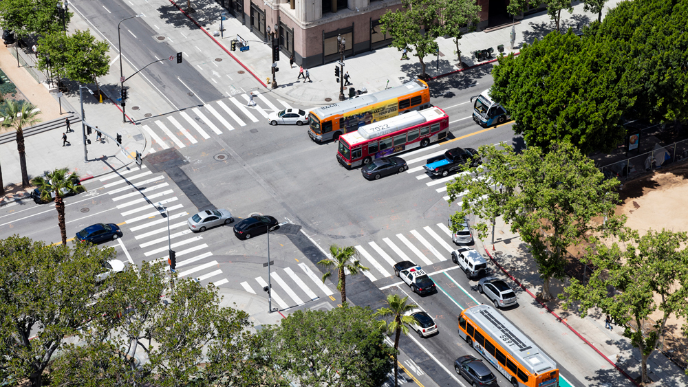 Cars and city buses passing through an intersection in an urban downtown area.