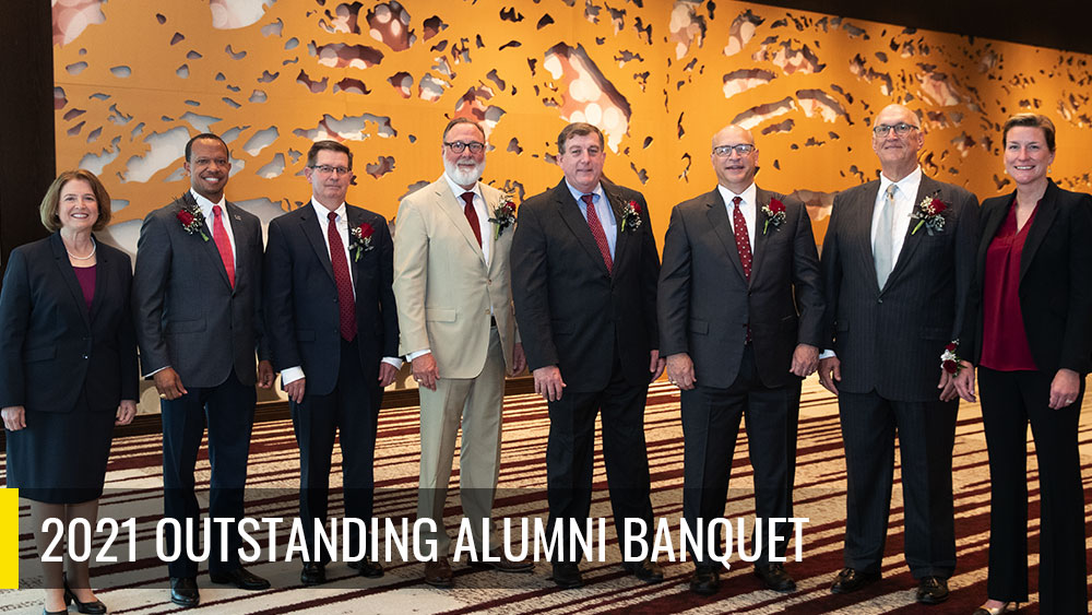 The words, 2021 Outstanding Alumni Banquet, over a photo of the following people standing in front of a mural at the banquet: M. Katherine Banks, Cedric J. Sims, James Peery, Mike A. Hernandez III, Kirk A. Shireman, Phillip McDivitt, Joe Wright and Starlee Sykes.