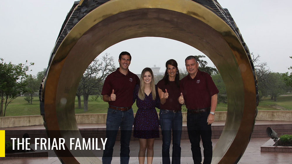 The Friar family taking a photo in front of the Aggie Ring at the Association of Former Students. 