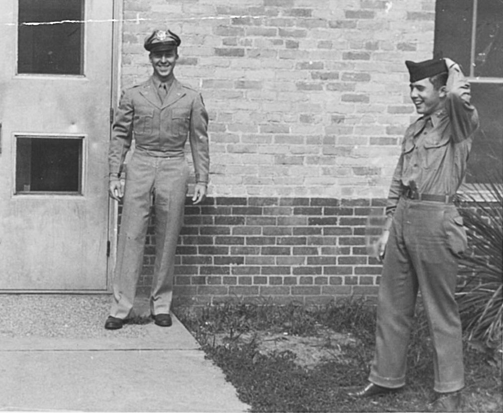 Black and white image of two Corps of Cadet male students smiling and standing outside of a Texas A&amp;M University dorm.