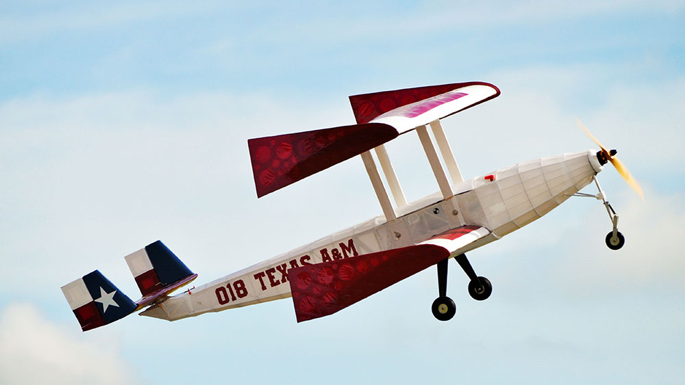 Red, white and blue Texas flag-themed biplane remote-controlled aircraft flying.