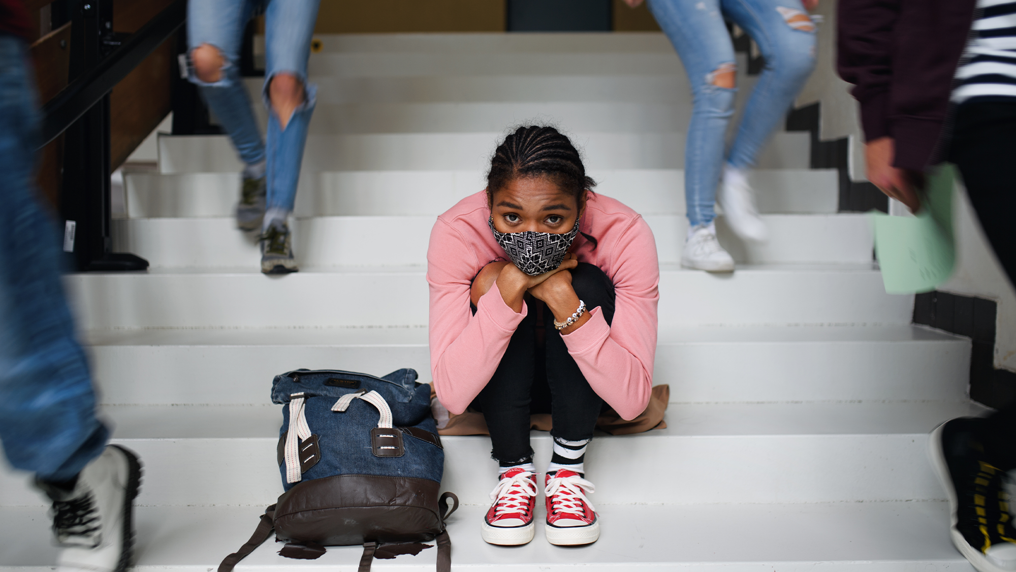 A student sits on the steps while other students are walking to class