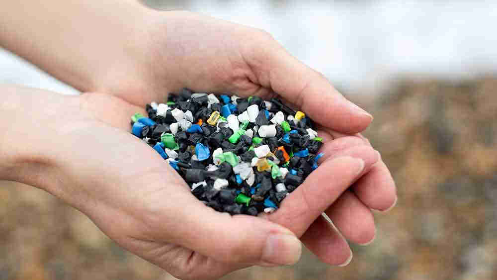 Close-up of hands holding plastic granules polluting beach