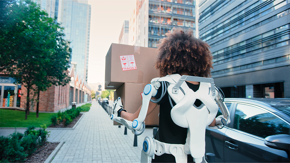 A woman carrying a box wearing an exoskeleton
