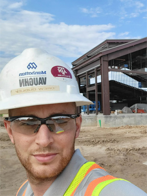 Man with hard hat outside a construction site
