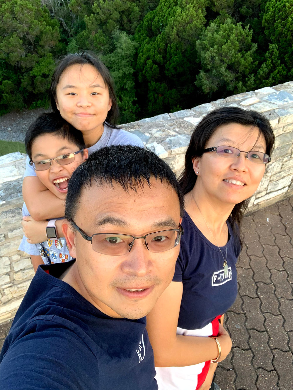 Dr. Zhou Li taking a selfie with his wife, daughter, and son while outside working out.