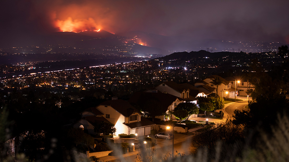 Photo of a neighborhood at night with wildfires in the distance.