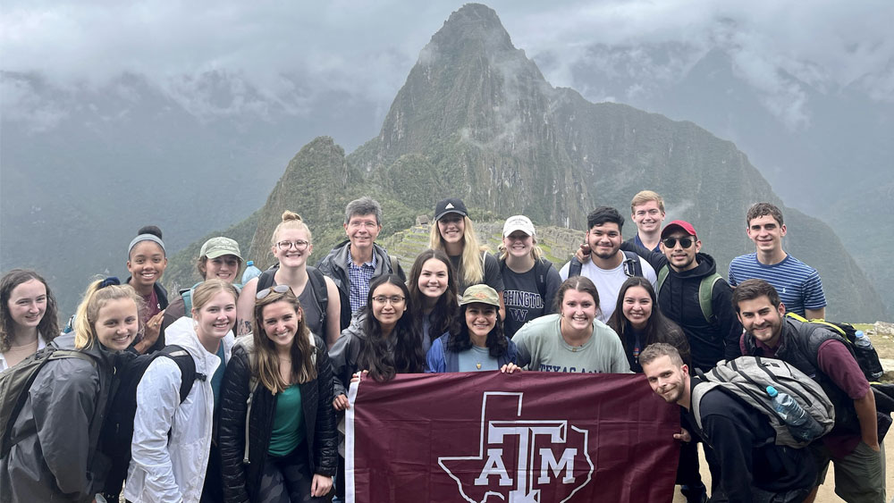 A group of students with a flag at Machu Picchu in Peru