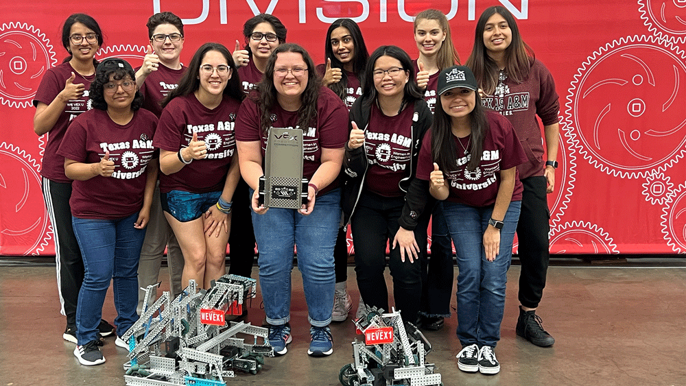 Group of girls posing with trophy and robots.