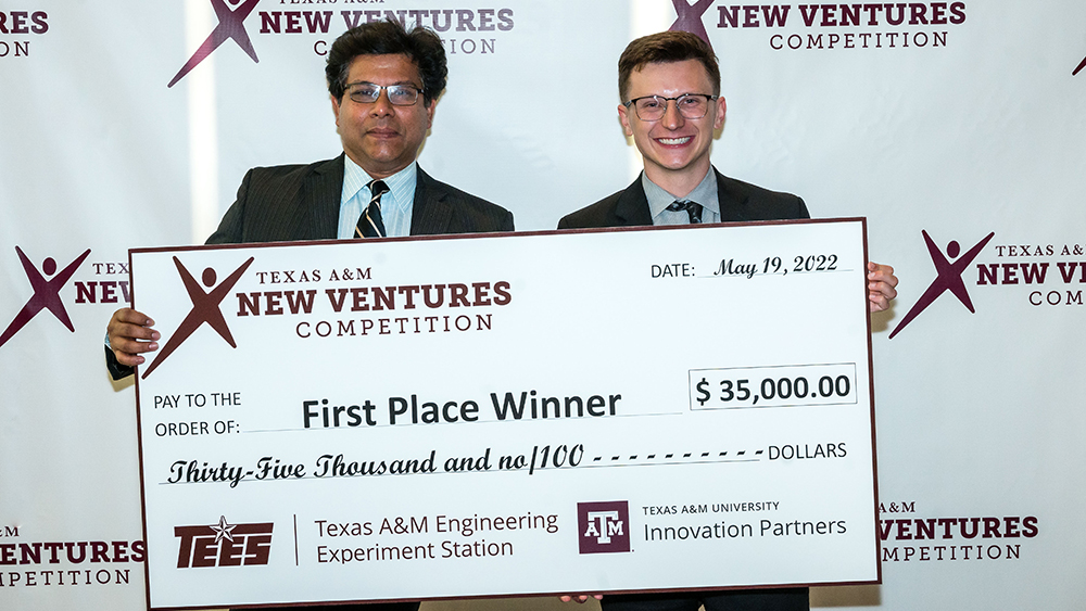 Dr. Saurabh Biswas and Bryton Praslicka holding a large first-place check for $35,000 from the Texas A&amp;M New Ventures Competition. Texas A&amp;M Engineering Experiment Station and Texas A&amp;M University Innovation Partners logos are at the bottom of the check.