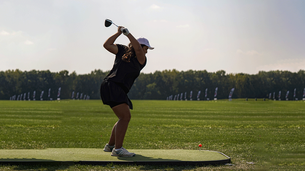 Katie Calderon mid-swing about to hit a golf ball 