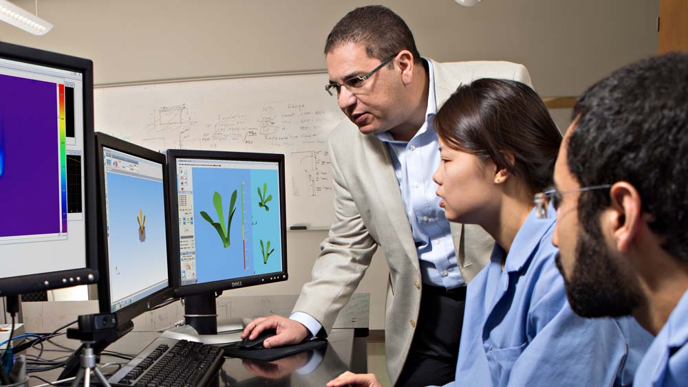 Male faculty member and two students view a 3D drawing model on a computer.