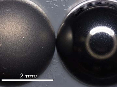 Two silver spheres barely touching each other. They are each about 2 mm in diameter.
