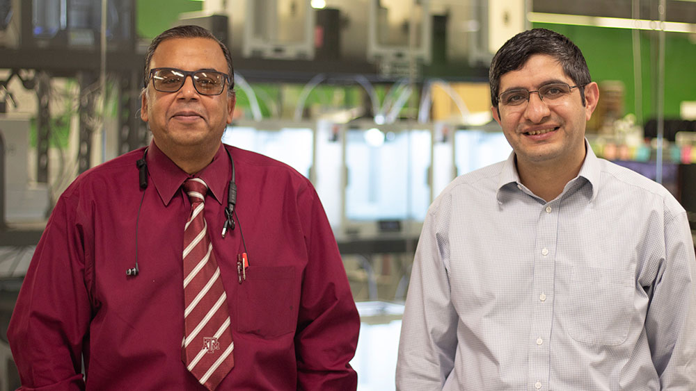 Dr. Debjyoti Banerjee and Dr. Hadi Nasrabadi smiling and standing in front of a bank of 3D printers in the Zachry Engineering Education Complex at Texas A&amp;M University