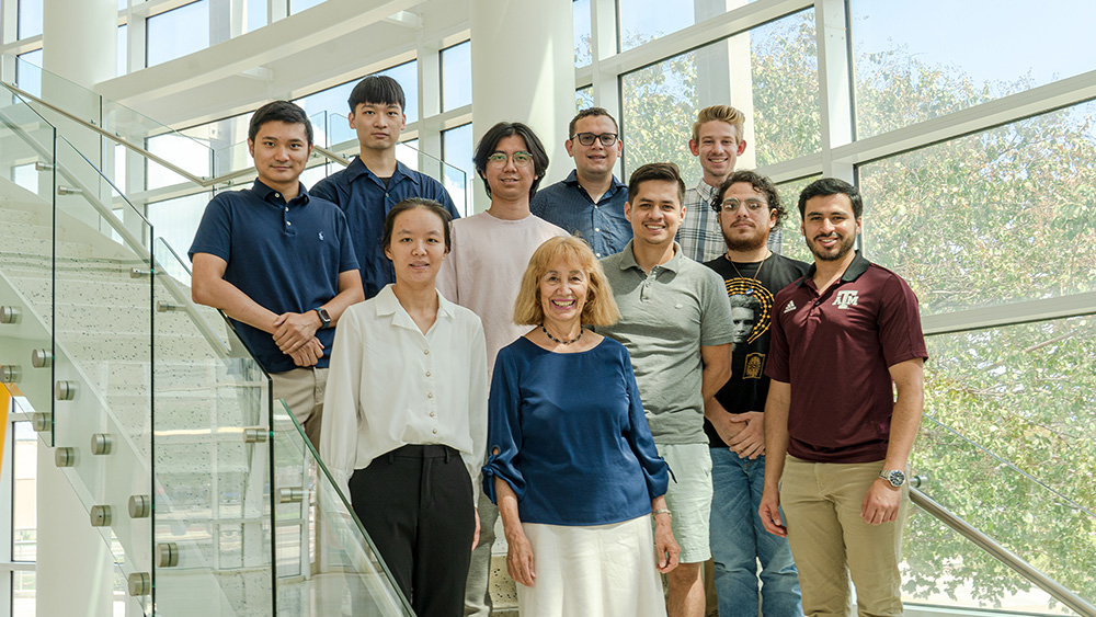 Dr. Perla and her research group, consisting of nine students, standing on the stairs of the Jack E. Brown Engineering Building. 