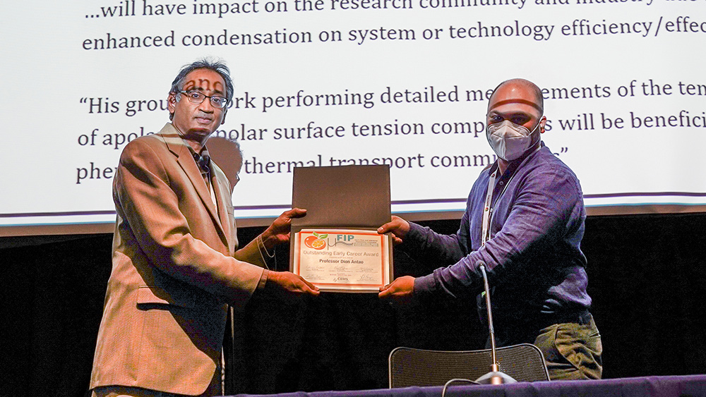 Dr. Dion Antao being handed an award at the 2022 Micro Flow and Interfacial Phenomena conference