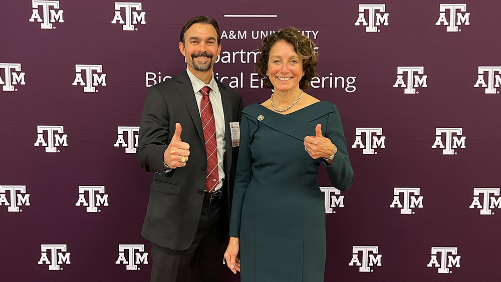 Drs. Mike McShane and Susan S. Margulies give thumbs up in front of a Texas A&amp;M banner.