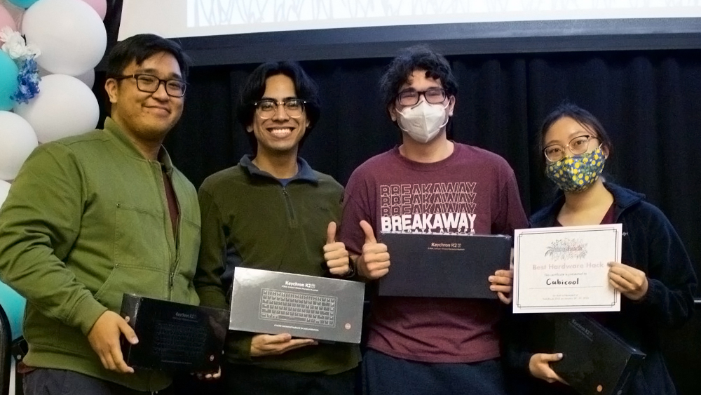 Members of the Cubicool team stand side by side, each holding boxed keyboards and the Best Hardware Hack award certificate for the team.